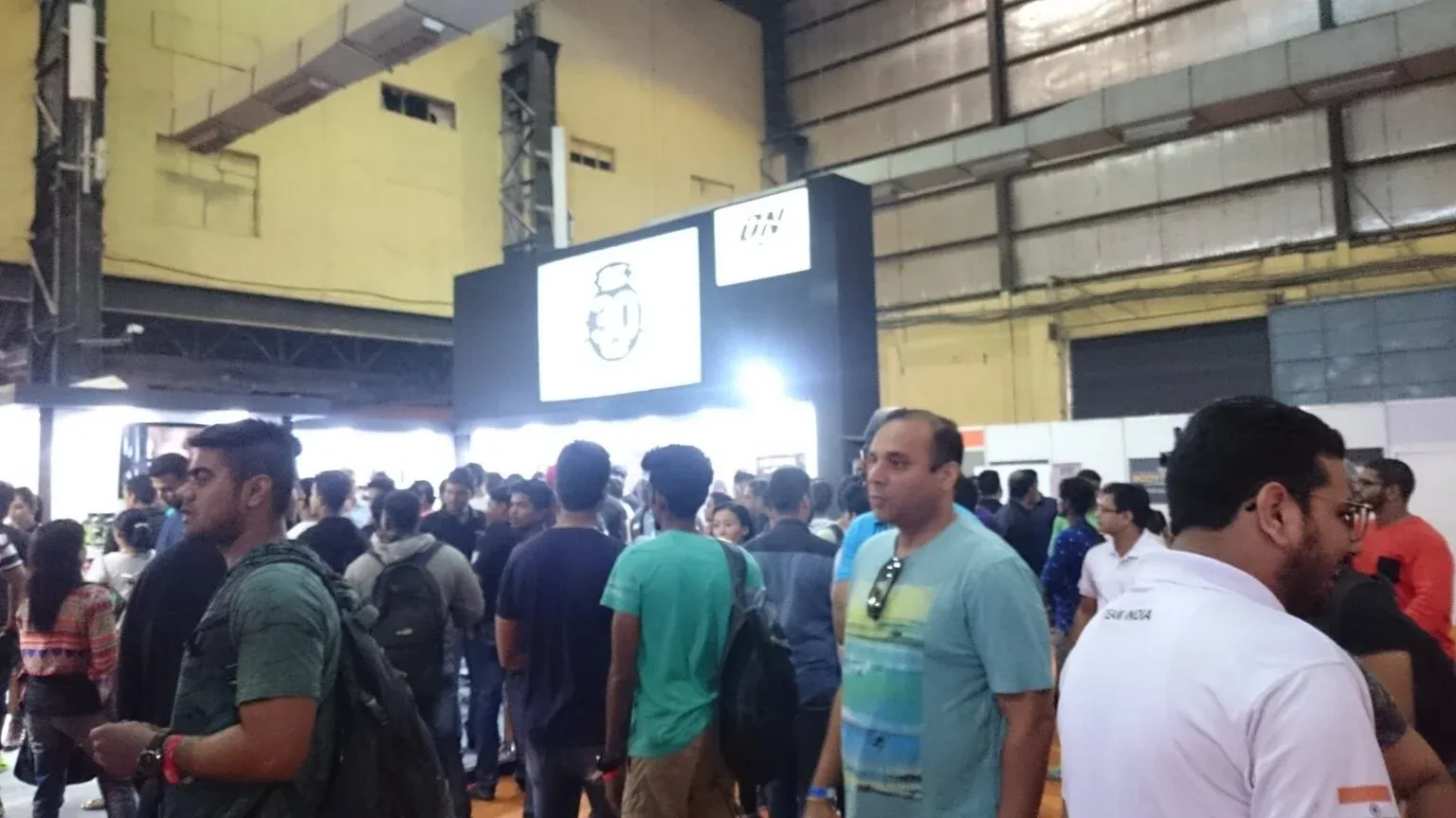 Visitors gathered around a large illuminated display screen in an exhibition hall.