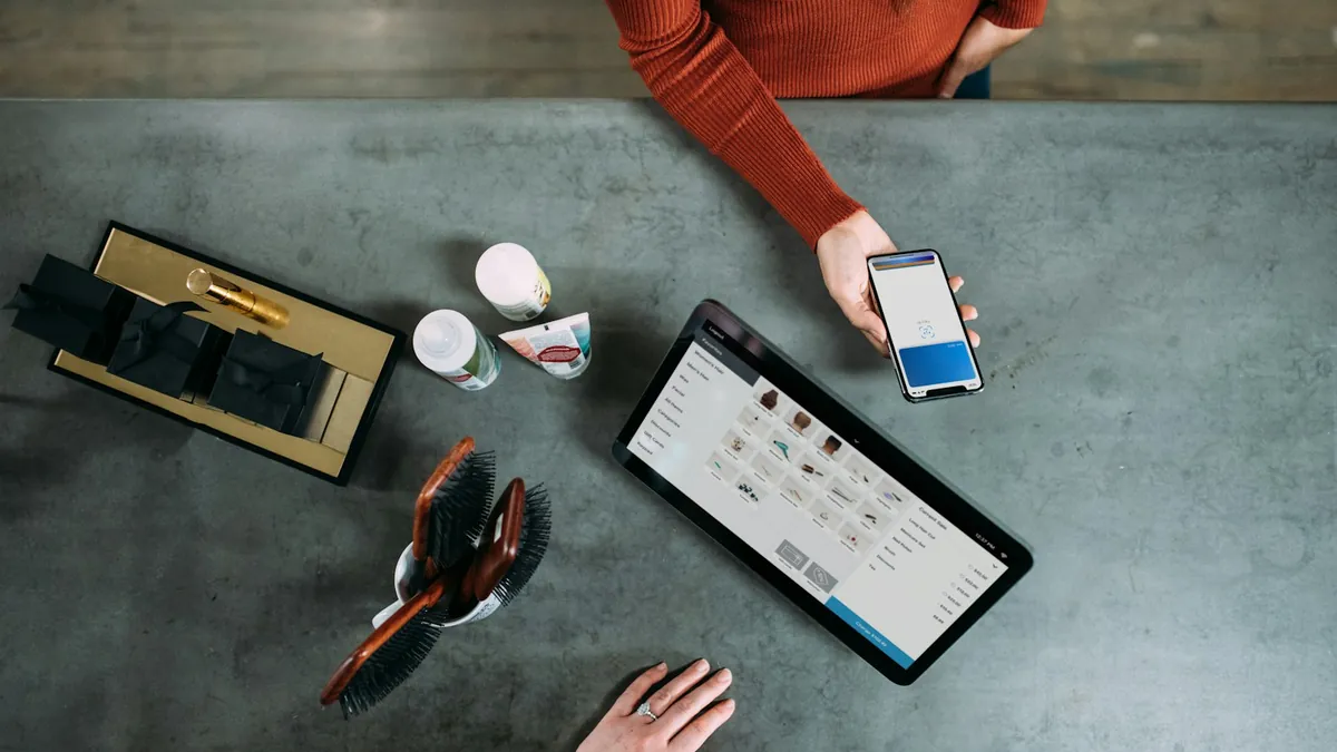 Overhead view of a customer paying by smartphone beside a tablet point-of-sale
